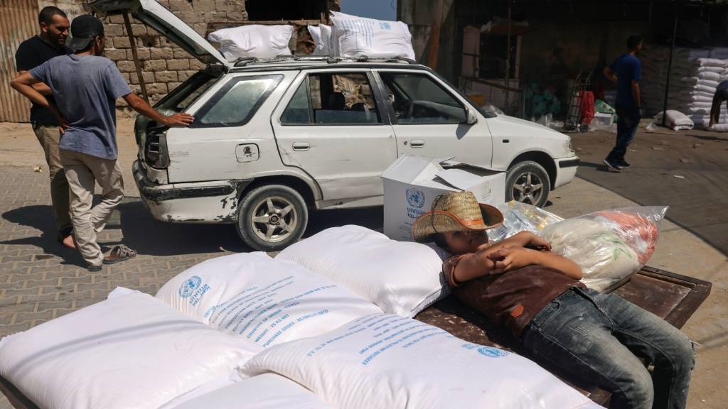 A Palestinian youth rests on bags of aid at the Un