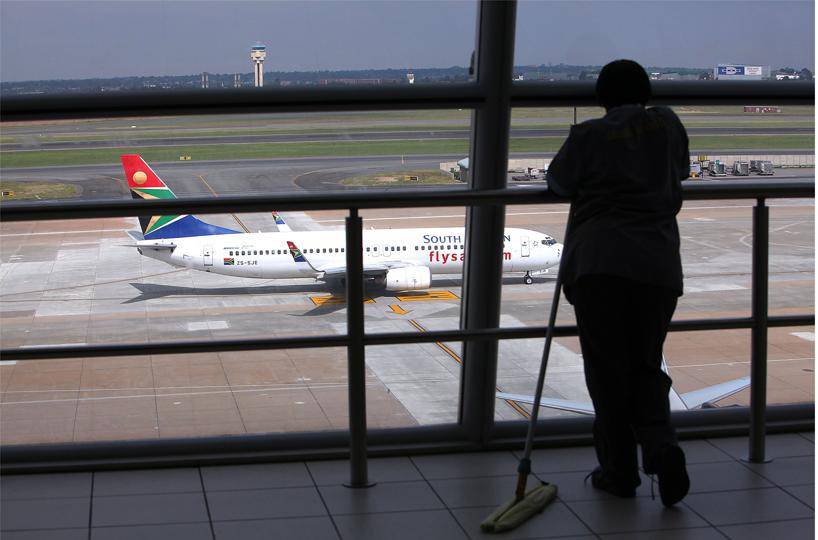  An airport cleaning staff member looks out to a grounded SAA aircraft on the runway at OR TamboInternational Airport in Johannesburg. Picture: Alon Skuy / The Times / Gallo Images