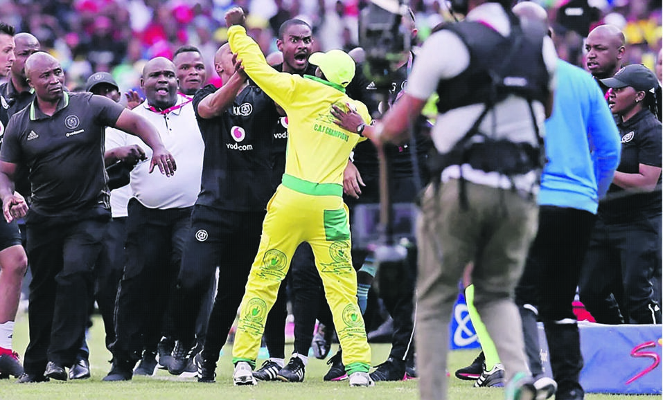 An unidentified Mamelodi Sundowns fan is stopped by the Orlando Pirates security personnel from attacking Bucs assistant coach Rulani Mokwena at last weekend’s game. Picture: Daily Sun