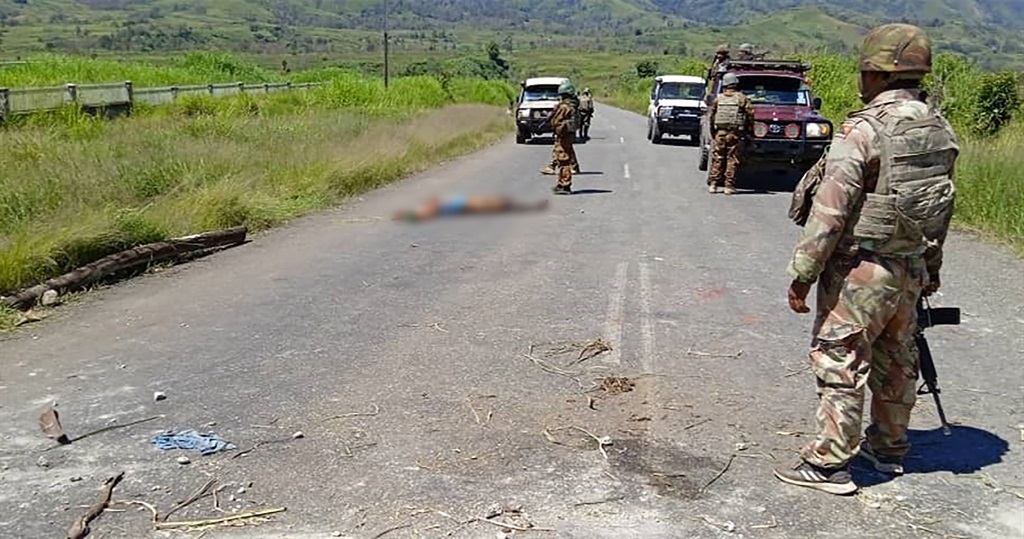 This handout picture released by the Royal Papua New Guinea Constabulary on 19 February 2024 shows a dead body on a road as officials patrol near the town of Wabag, 600 kilometres northwest of the capital Port Moresby. 