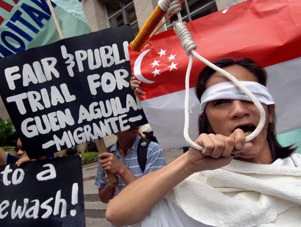 Protesters stage a demonstration with one pretending to undergo a mock hanging outside the Singaporean embassy in Manila.
