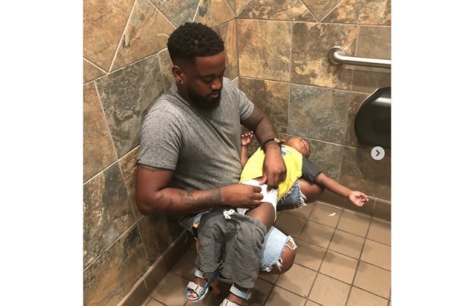 Donte Palmer changing his 1-year-old son Liam's nappy in a public toilet. 3boys_1goal