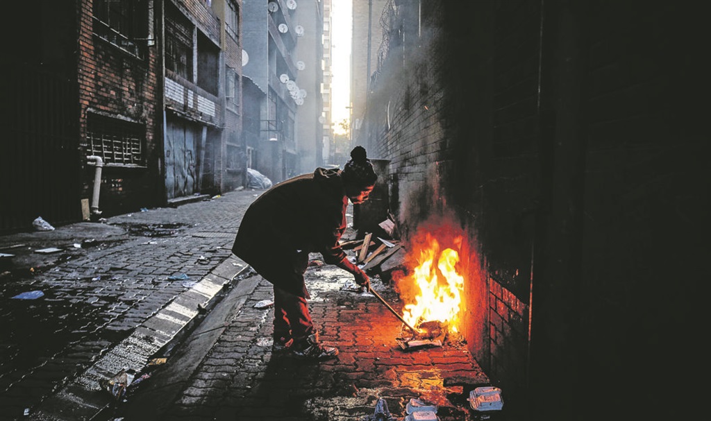 BONFIRE A homeless drug addict tends a fire on a pavement in Hillbrow. He and his friends hide in dark passageways and smoke their nyaope, a combination of drugs that includes heroin. It is the cheapest drug for addict. Picture: Mpumelelo Buthelezi