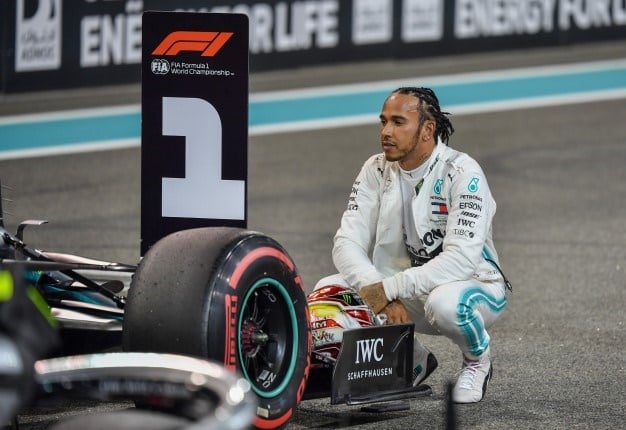 Mercedes' British driver Lewis Hamilton sits next to his car as he celebrates winning the pole position after the qualifying session at the Yas Marina Circuit in Abu Dhabi, a day ahead of the final race of the season, on November 30, 2019. ANDREJ ISAKOVIC / AFP