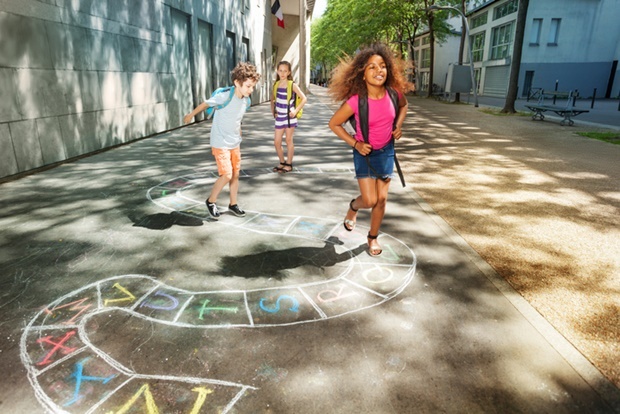 Group of kids jumping and paying hopscotch game ou