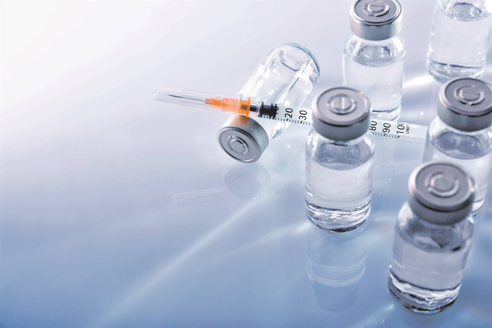 Vials with medication and syringe on blue methacrylate table. Horizontal composition. Top elevated view. Picture: Supplied
