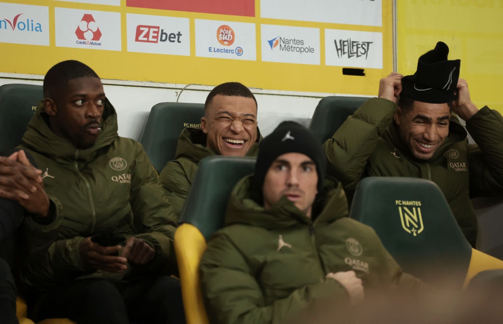NANTES, FRANCE - FEBRUARY 17: Kylian Mbappe between Ousmane Dembele and Achraf Hakimi of PSG sit on the bench during the Ligue 1 Uber Eats match between FC Nantes (FCN) and Paris Saint-Germain (PSG) at Stade de la Beaujoire on February 17, 2024 in Nantes, France. (Photo by Jean Catuffe/Getty Images)