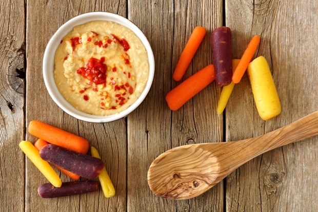 Baby rainbow carrots with hummus dip and spoon, ov