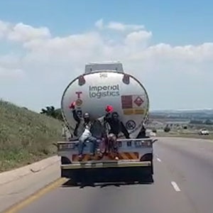 two men hitch a ride at the back of a truck