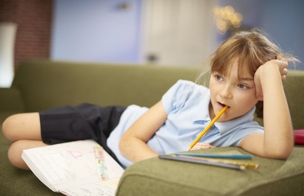 girl sitting on couch chewing pencil