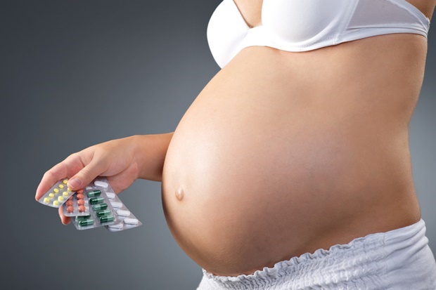 Pregnant woman holding vitamins in her hand