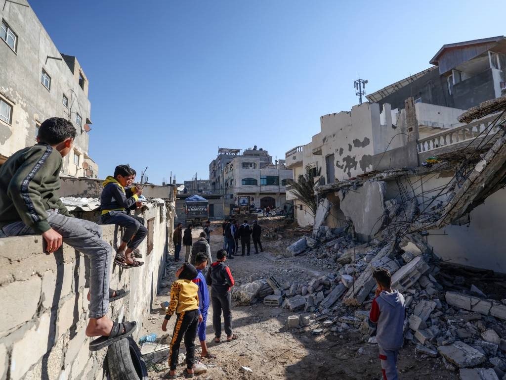 Çocuklar Filistinli işçilerin bir evi yıkmasını izliyor
