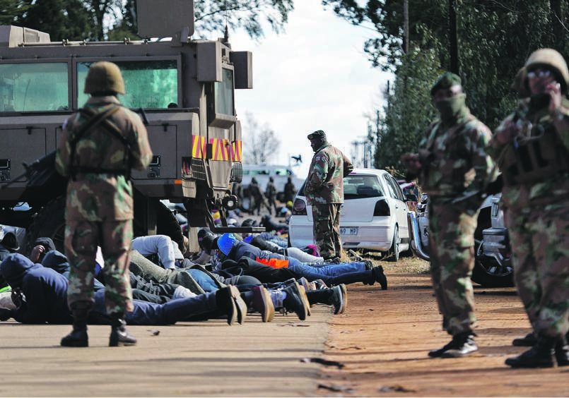 Members of the International Pentecost Holiness Church are ordered to lie down on the ground after being searched by the SA National Defence Force and police officers in Zuurbekom yesterday Picture: Tebogo Letsie