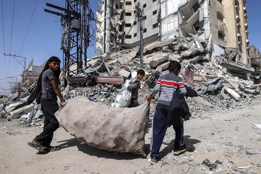 Boys walk with a large sack containing collected plastic past the rubble of a destroyed building in Rafah in the southern Gaza Strip. (Mohammed Abed/ AFP)