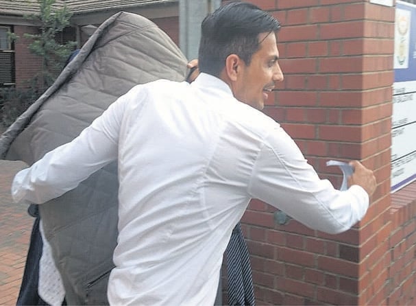 Farhad Hoomer hides his face while being escorted out of the Verulam Magistrate’s Court by his attorney, Yusuf Cassim.