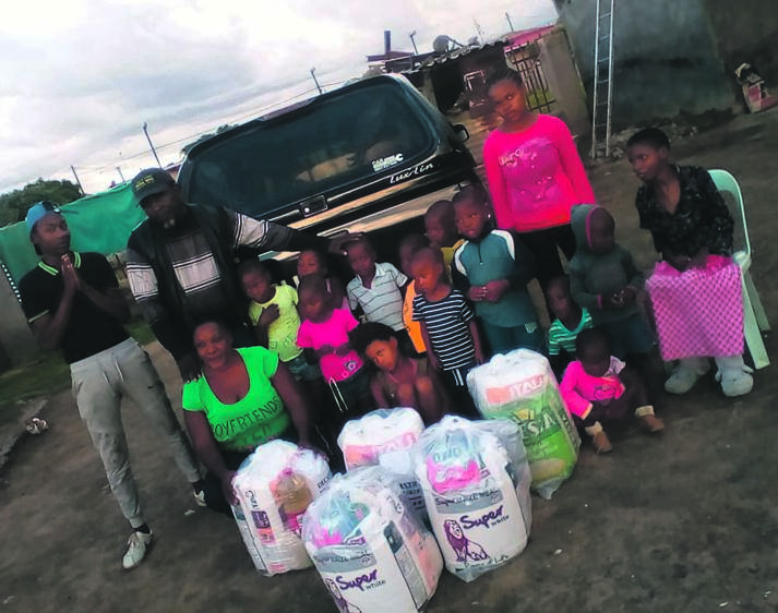 John Mbeleko (back, second from left) handed groceries to Nthabiseng Tsheole (front, left) and the kids at a shelter in Botshabelo on Wednesday. 