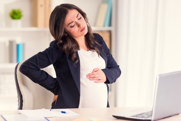  Enfermedad de espalda. Una mujer embarazada joven retiene, w