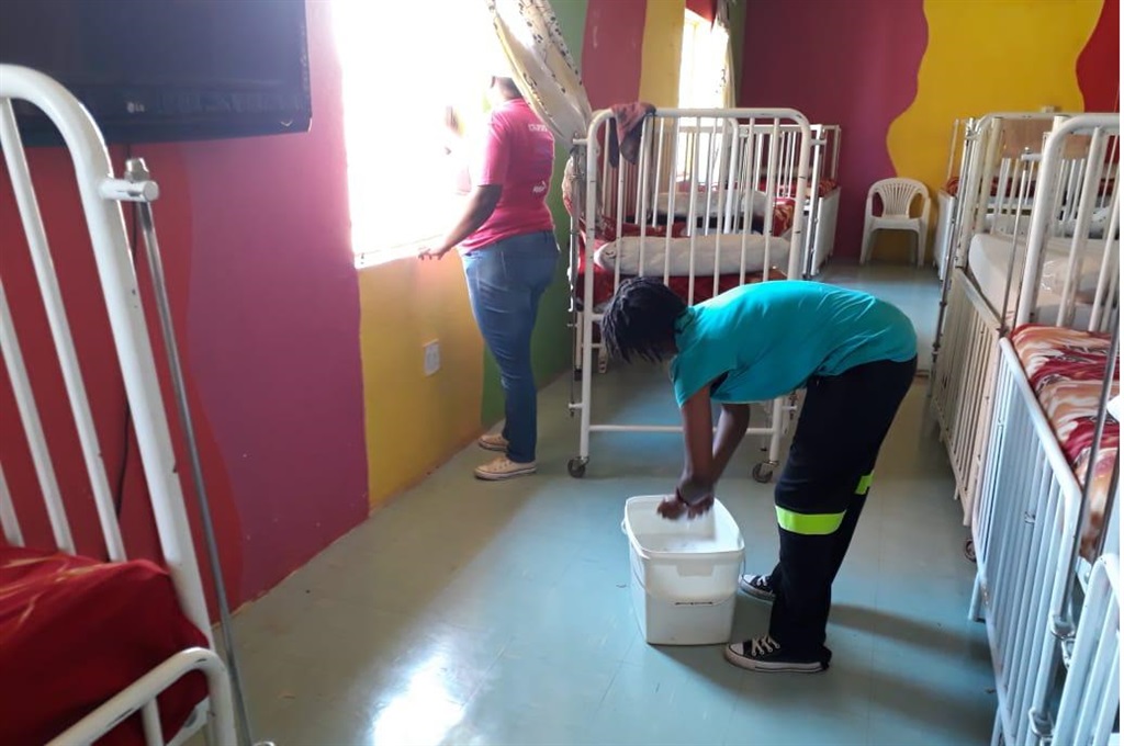 Cops clean one of the rooms at Korekile Home for cerebral palsied children in Simunye, Westonaria. 