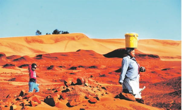 Mablasi Yalo (67) and her four-year-old  granddaughter Azola walk along the red dunes in Xolobeni near Mbizana, Eastern Cape. The community has been fighting for years to stop a titanium mine from being built there. Picture: Leon Sadiki
