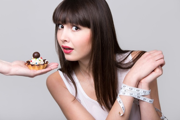 Young dieting woman with hands tied with measureme