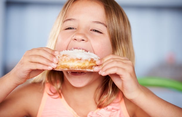 Girl eating sugary donut 