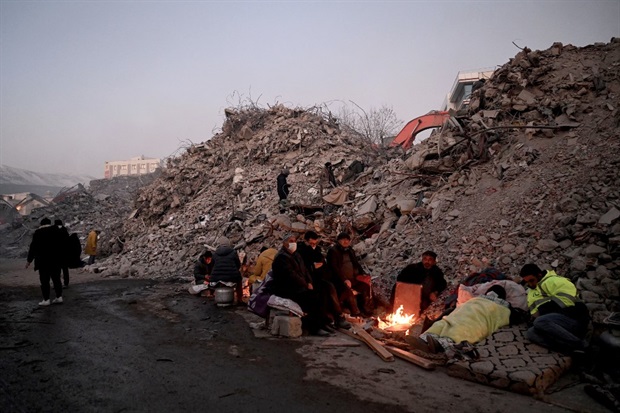 <p>Relatives warm up around a fire in front of rubble of collapsed buildings as rescue teams continue to search victims and survivors, after a 7.8 magnitude earthquake struck the border region of Turkey and Syria earlier in the week, in Kahramanmaras on 12 February 2023.</p><p><em>(PHOTO: OZAN KOSE / AFP)</em></p>