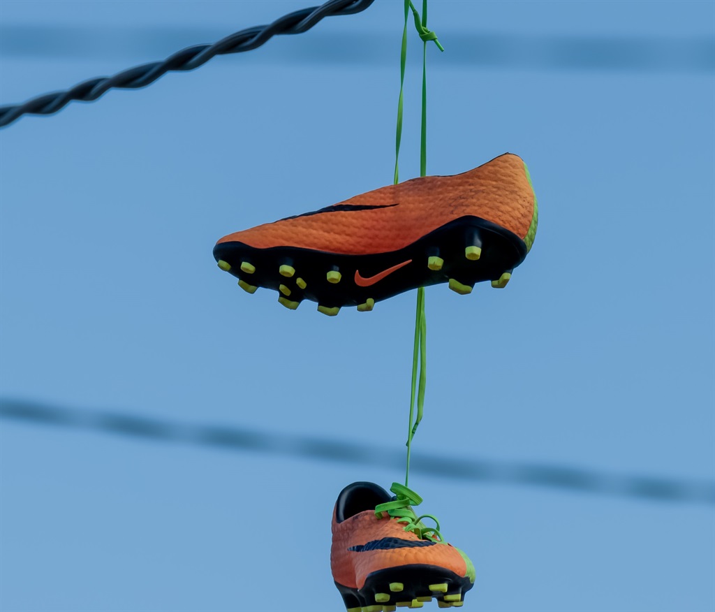 Orange and green Nike football shoes hanging from an electrical wire at Umina Beach, NSW, Australia.