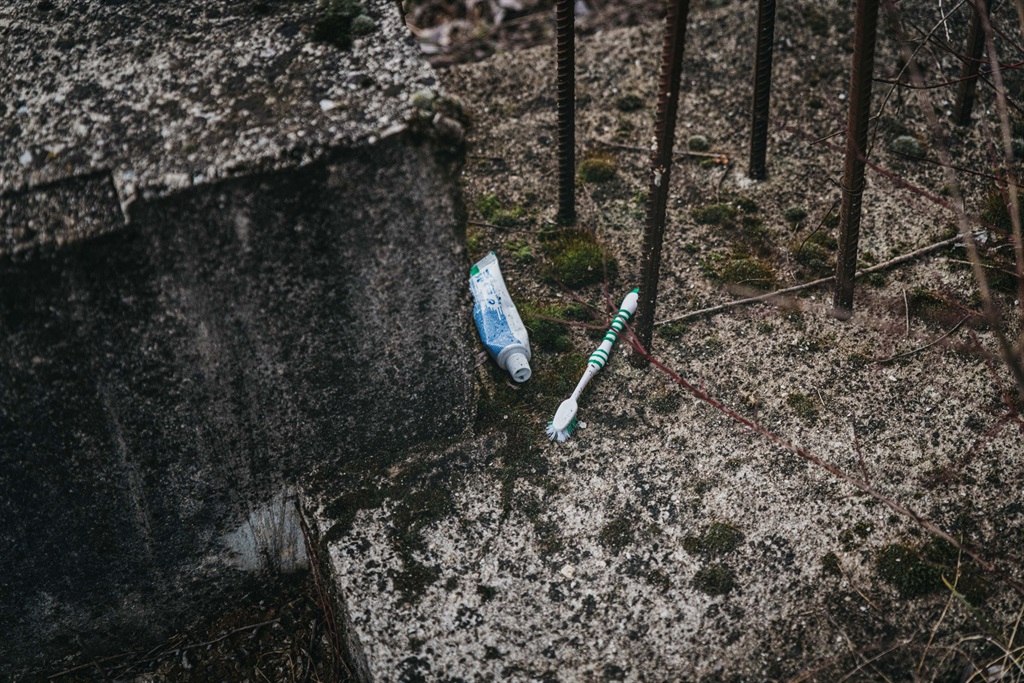A disposed toothbrush and toothpaste on the ground. 