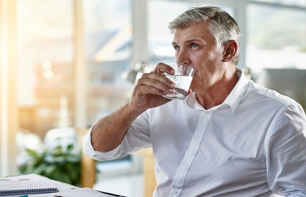 man drinking water at office desk 