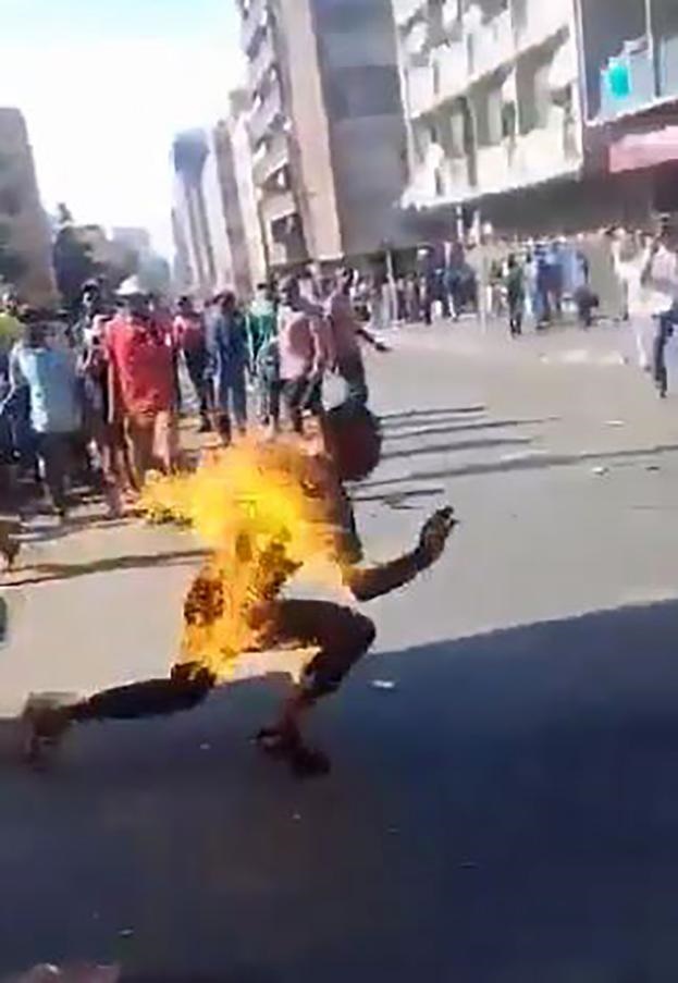 FIERY DEATH: 
People watch a man try to escape his fate.