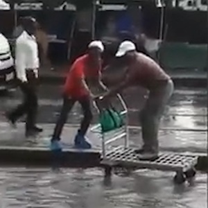 Joburg trolley pushers assist pedestrians to cross a flooded road. (Screengrab)