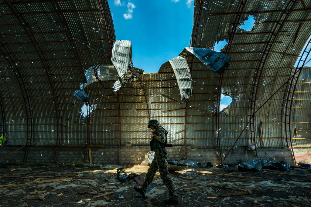Seorang tentara Ukraina berjalan di dalam gudang yang hancur 
