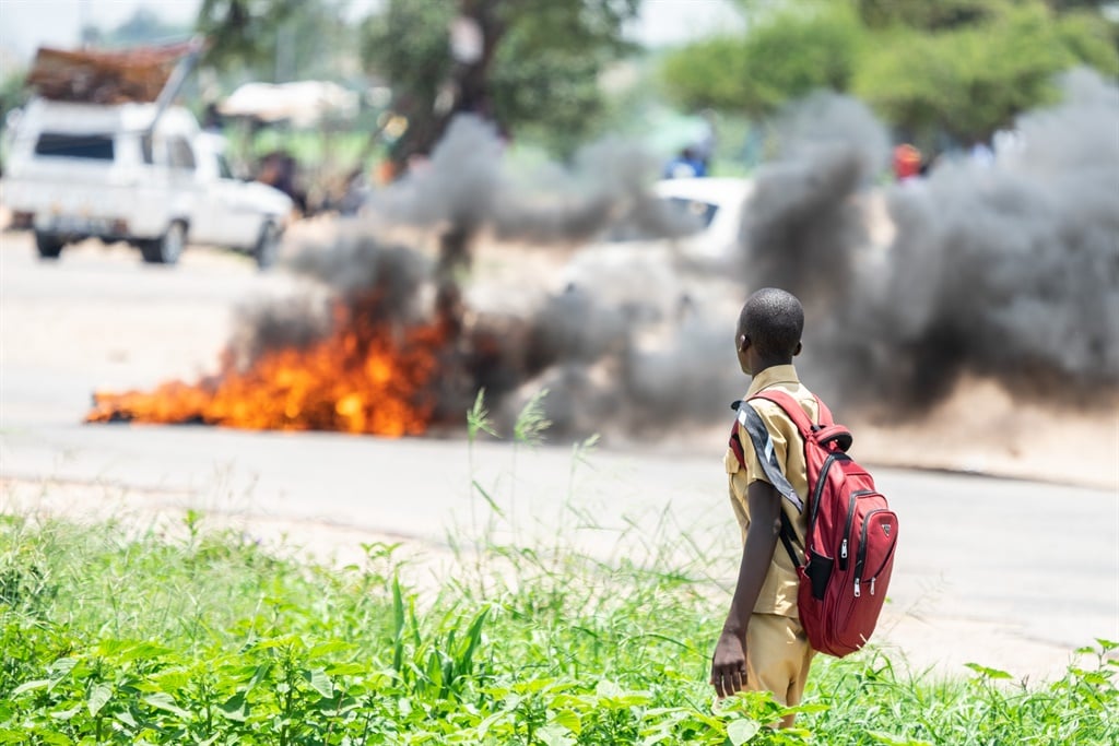 A school boy looks at a burning barricade during a shutdown demonstration in Bulawayo, Zimbabwe (Zinyange Auntony/Getty Images)