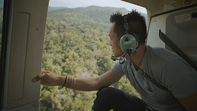 National Geographic Explorer, Albert Lin, looks out on the land below during a helicopter flight to the El Zotz archaeological site. (Photo: National Geographic)