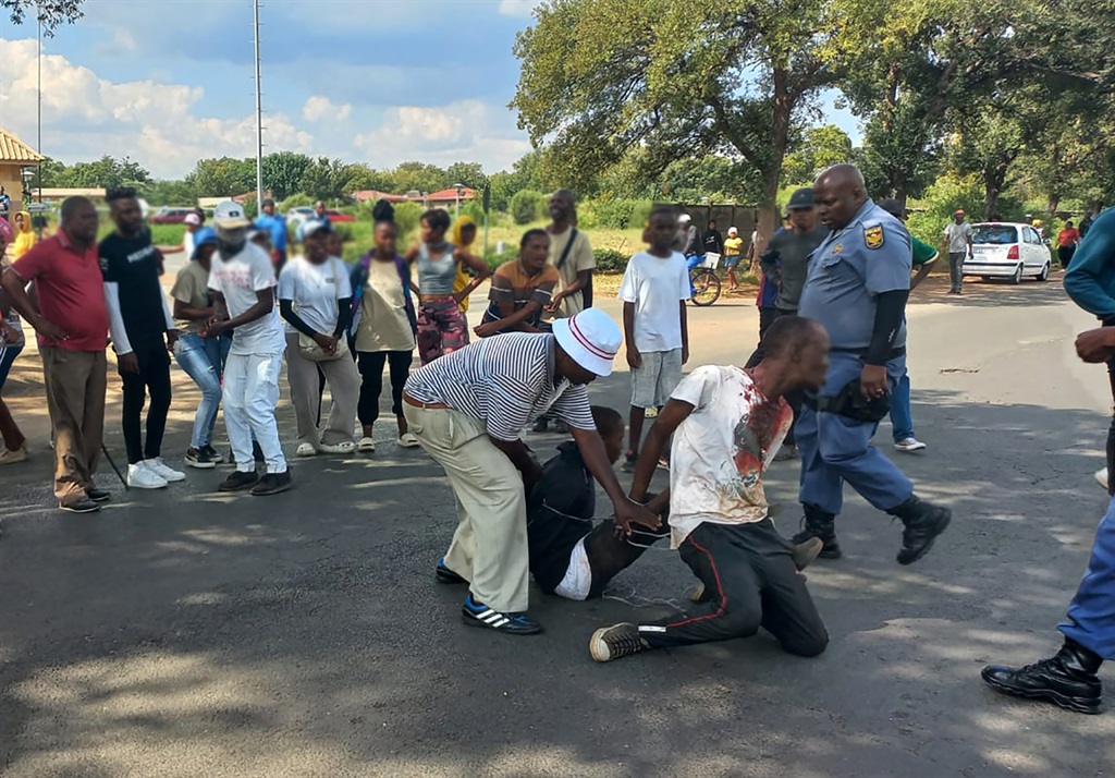 Police rescue two men from residents who accused them of murder. Photo by Tumelo Mofokeng