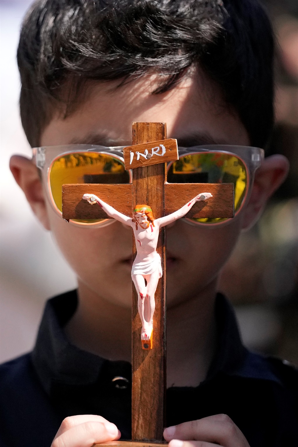A young boy holds a crucifix during a procession t