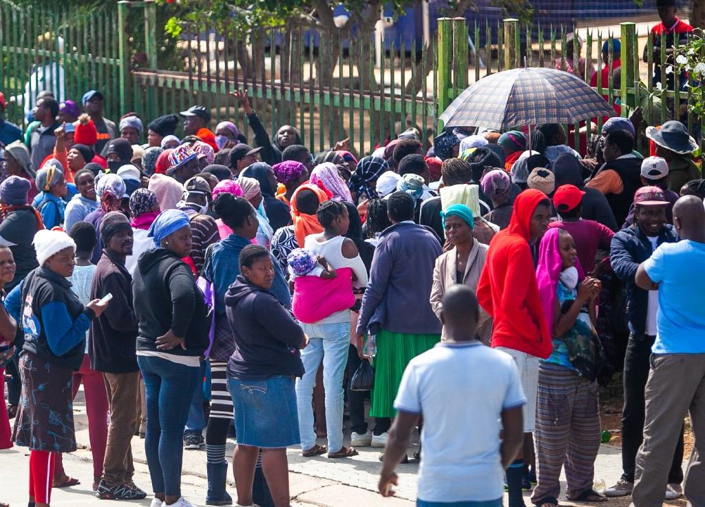 A general view of people queuing for food parcels at a local school.