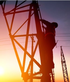 Worker at an electric substation with sunset background