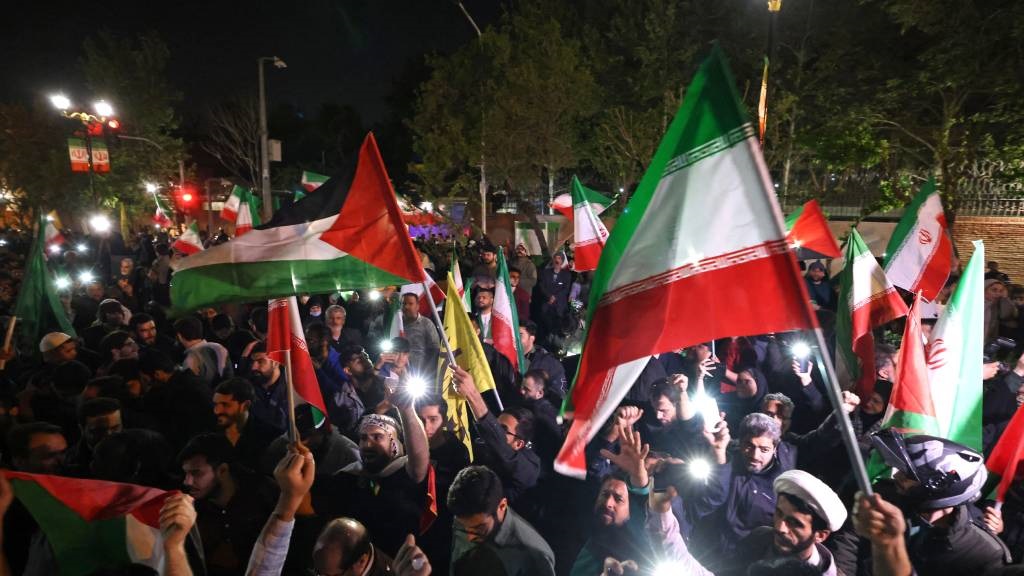 تظاهرکنندگان پرچم های ایران و فلسطین را به اهتزاز در می آورند