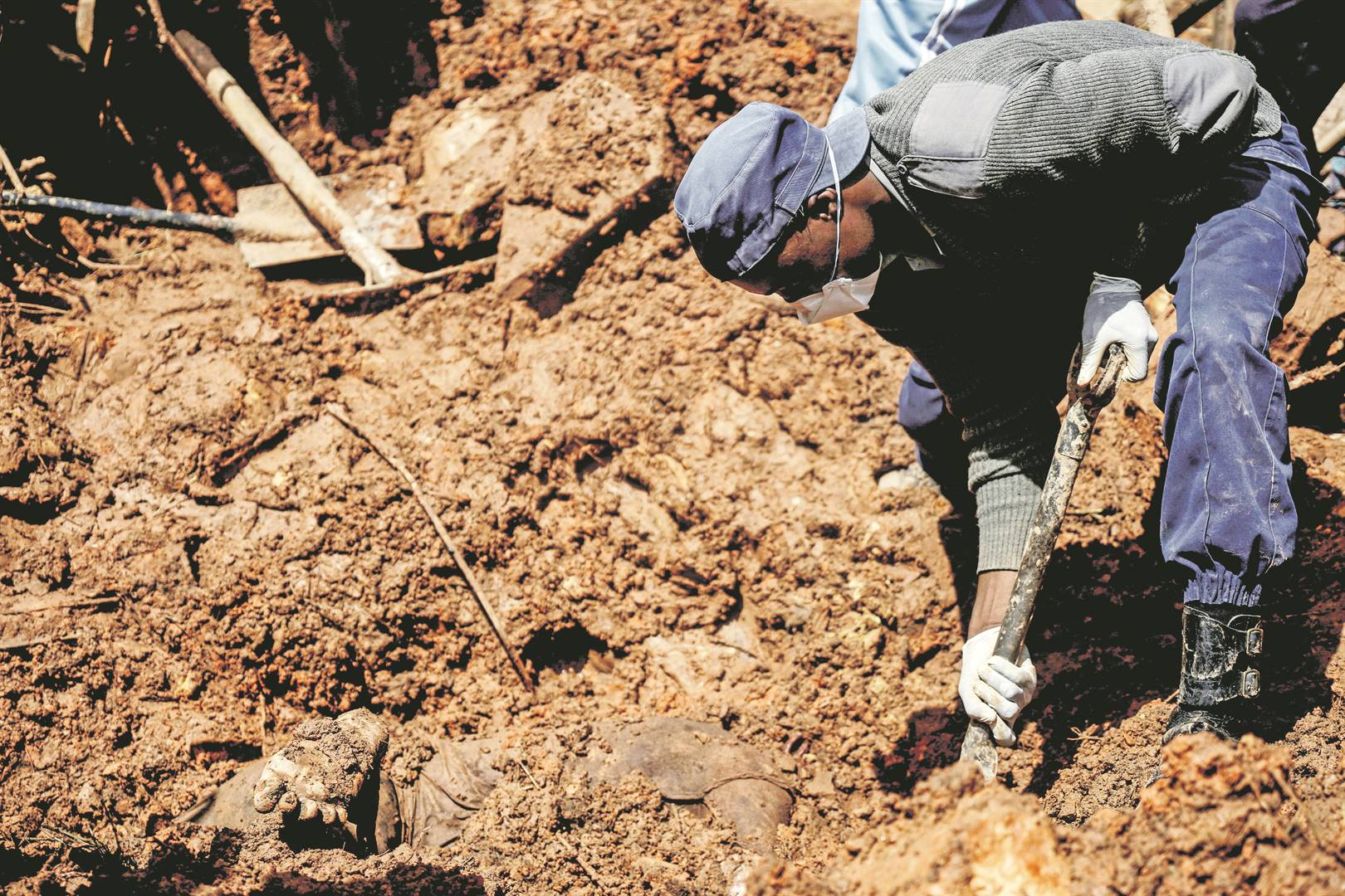 A policeman helps to dig for the body of 17-year-old Agreement Munanga. Picture: AP / KB Mpofu