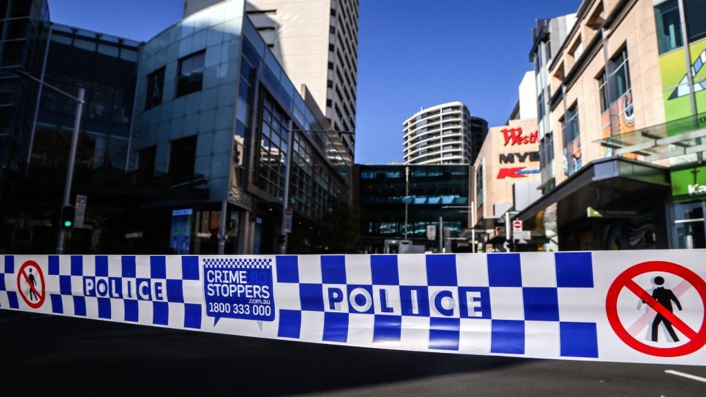 Police tape can be seen in front of a roadblock outside the Westfield Bondi Junction shopping mall in Sydney, a day after a 40-year-old knifeman with mental illness roamed the packed shopping centre killing six people and seriously wounding a dozen others. (David Gray/AFP)