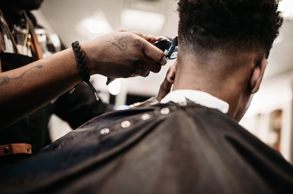 A man gets his hair cut by a skilled stylist at a small business barbershop.