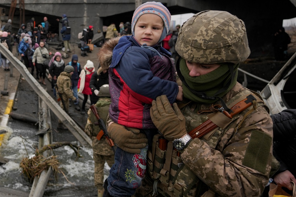 A Ukrainian serviceman holds a child crossing the Irpin river on an improvised path under a bridge, that was destroyed by Ukrainian troops designed to slow any Russian military advance, while fleeing the town of Irpin, Ukraine, Saturday, March 5, 2022. What looked like a breakthrough cease-fire to evacuate residents from two cities in Ukraine quickly fell apart Saturday as Ukrainian officials said shelling had halted the work to remove civilians hours after Russia announced the deal. (AP Photo/Vadim Ghirda)