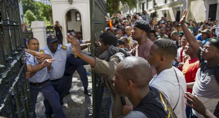 South African students protest outside the parliament precinct before forcing their way through the gates of parliament on October 21, 2015 in Cape Town, South Africa. Protesting students broke through the gates of parliament during protests against a proposed hike in tuition fees, this is part of the #FeesMustFall movement. (Photo by Gallo Images / Beeld / Jaco Marais)