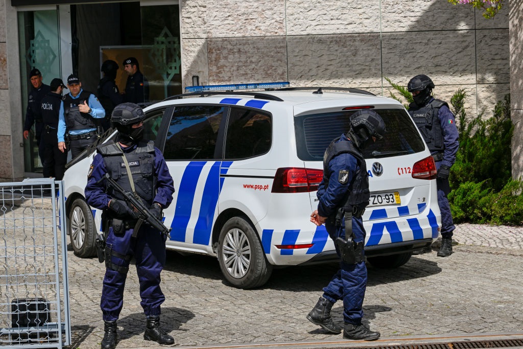 Mask-clad members of the PSP stand guard as a police vehicle enters the Ismaili Center where an attacker stabbed to death two women on March 28, 2023, in Lisbon, Portugal.
