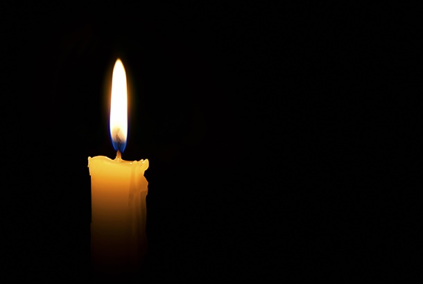 Single lit candle with quite flame on black background.