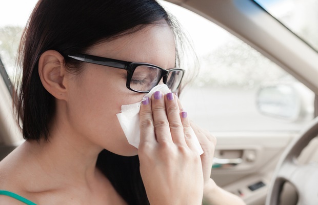 Woman blowing her nose in car 