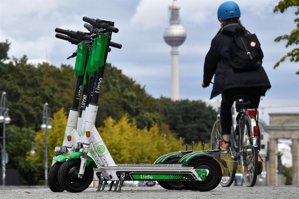 A woman cycles past a some parked e-scooters.