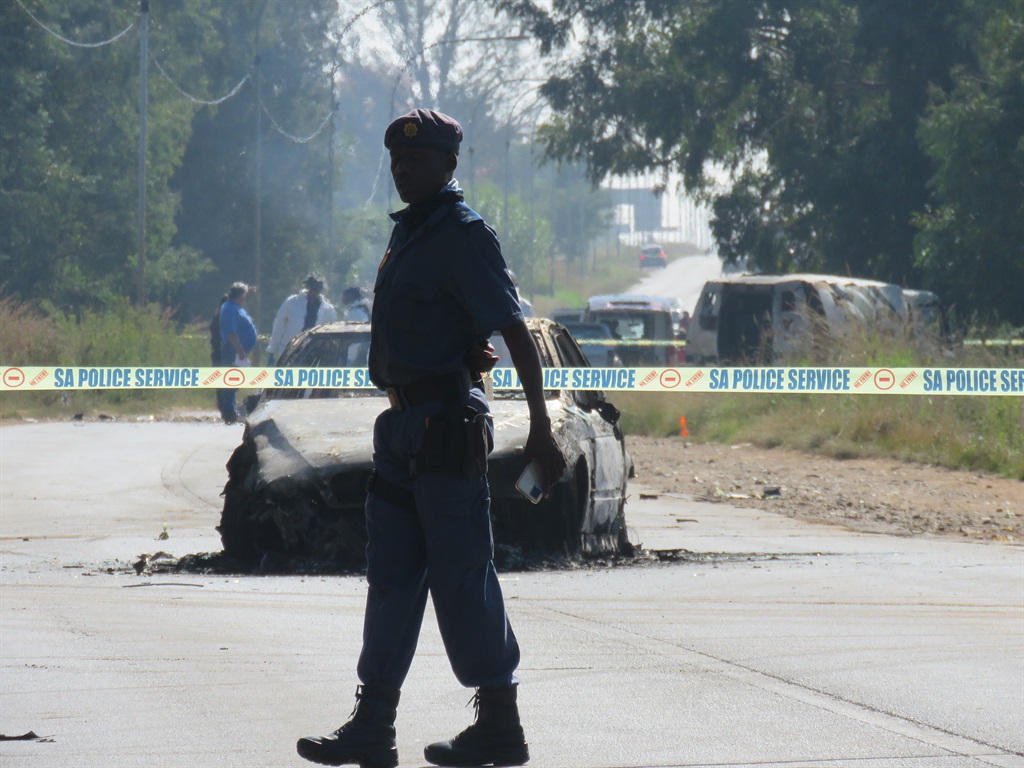 A cop at the scene where a cash van and the suspects' BMW went up in flames on Putfontein Road near Chief Luthuli kasi in Ekurhuleni on Wednesday, 5 April. Photo by Ntebatse Masipa
