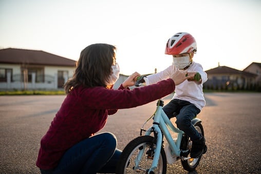 Mother teaches her kid how to ride a bicycle both 
